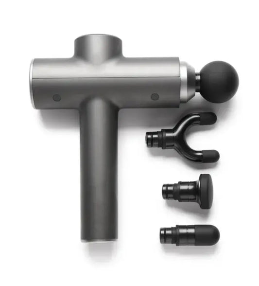 Compact mini massage gun with four heads on a gym bench – perfect for muscle recovery and portable pain relief.
